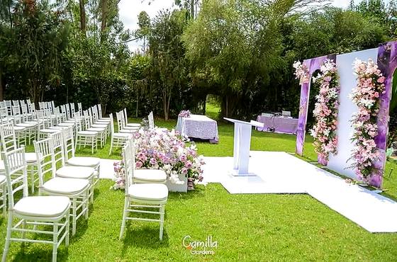 White chiavari chairs in rows on the lawn beside a ceremony arch draped in pink and white flowers