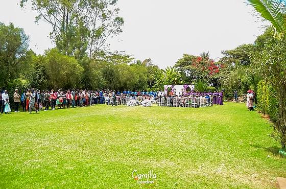 Several hundred guests seated in a wide arc across the main lawn at Camilla Gardens