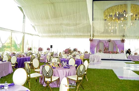 Lilac and white reception tables with floral centrepieces under a draped marquee ceiling