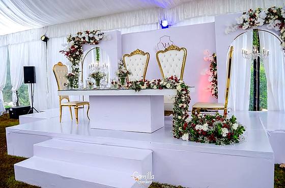 Reception stage with gilded throne chairs, mirrored panels and tall floral columns either side