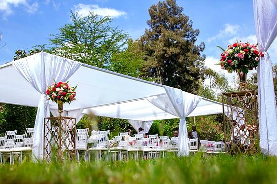 White marquee standing open to the garden with tall floral centrepieces on the tables inside