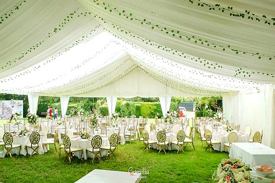 Round tables under a white marquee hung with ivy garlands, open to the garden
