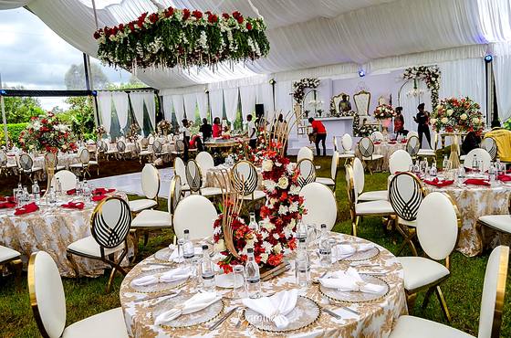 Marquee reception with a suspended floral ceiling above round tables set in red and gold