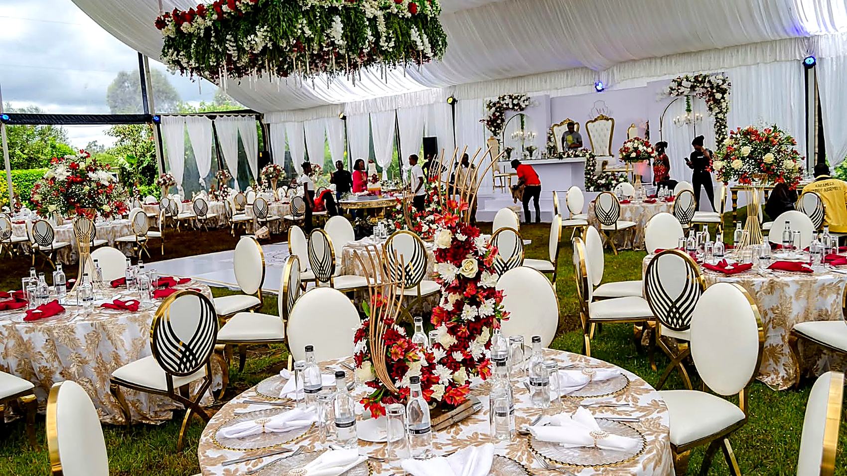 Marquee reception at Camilla Gardens with a suspended floral ceiling above round tables laid in red and gold