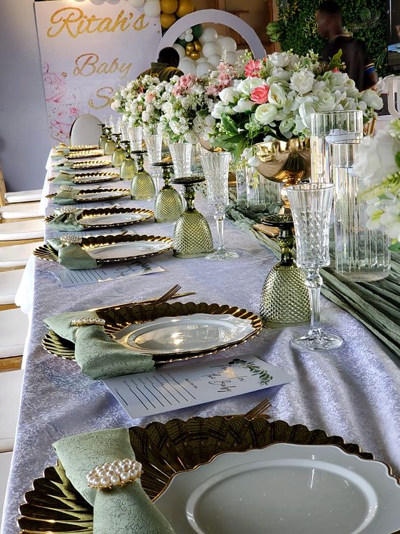 Ritah's baby shower table with gold scalloped chargers, sage napkins in pearl rings, green goblets and white and pink roses