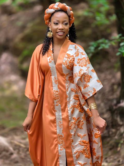 Woman in an amber and ivory brocade kimono walking along a forest path