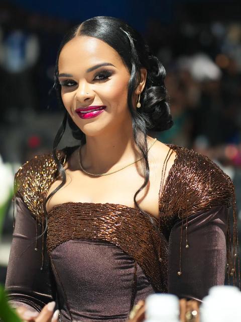 Smiling woman in a bronze beaded off-shoulder gown at an evening event