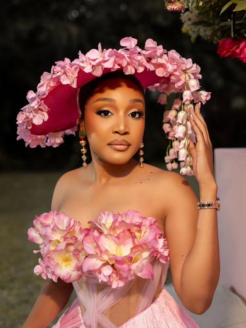 Woman in a pink floral wide-brim hat and matching flower corset at a garden event
