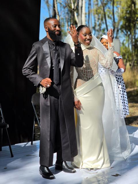 Bride waving and groom smiling as they make their entrance at an outdoor wedding